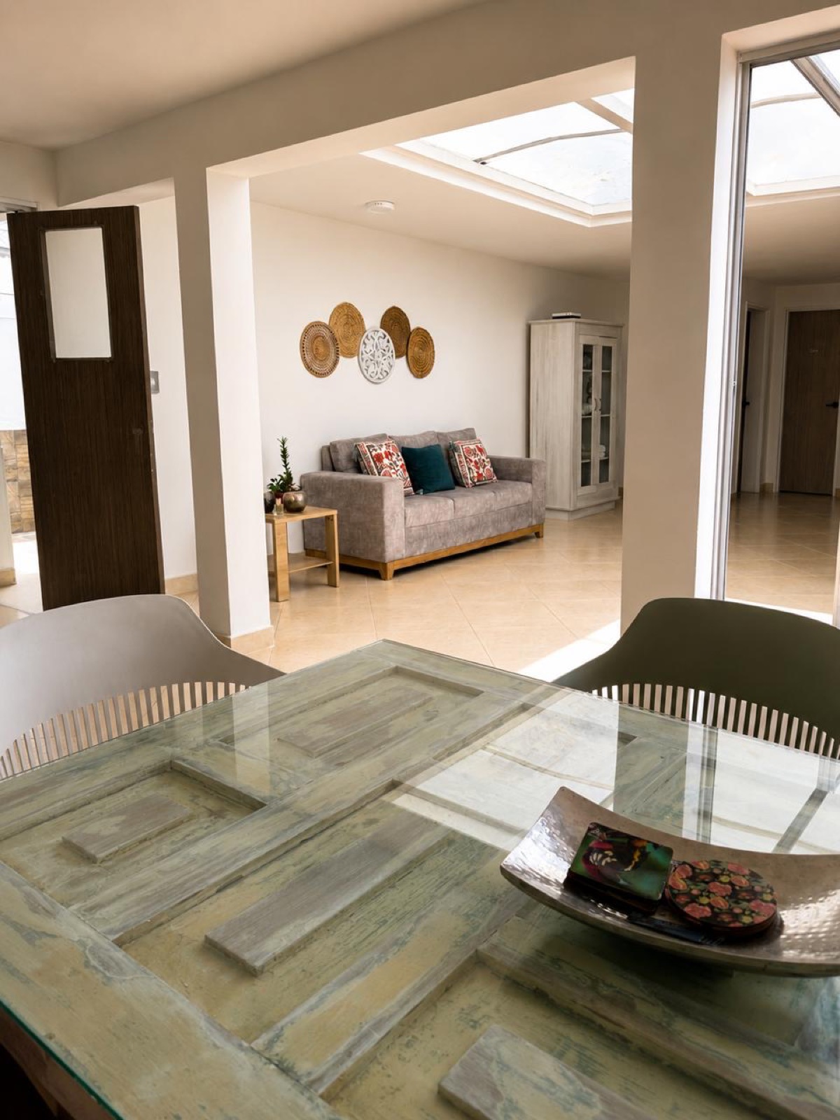 Glass-top dining table looking into the sunlit living space at Casa Verde